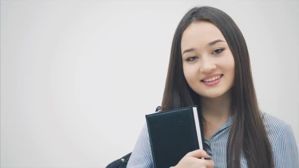 一个亚洲的女学生站在那里，肩上背着背包，怀里抱着书，竖起大拇指. — 图库视频影像