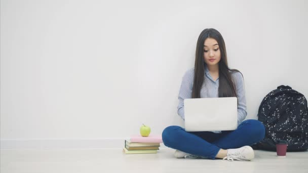 Aziatisch dame zitten op de vloer in loto positie, met laptop, nemen van pen en notebook uit haar tas, het schrijven van iets op. — Stockvideo