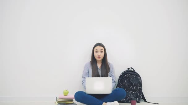 Bella sorridente studente asiatico seduto sul pavimento in posizione lotos, con il computer portatile, puntando le dita verso l'alto, sorridente . — Video Stock