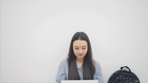 Mooie glimlachende Aziatische student zittend op de vloer in lotospositie, met laptop, wijzend haar vingers omhoog, glimlachend. — Stockvideo