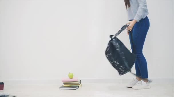 Adorable jeune fille asiatique apparaissant sur fond blanc, assise sur le sol en position lotos, saluant, ouvre son sac à dos, sortant le carnet de croquis . — Video