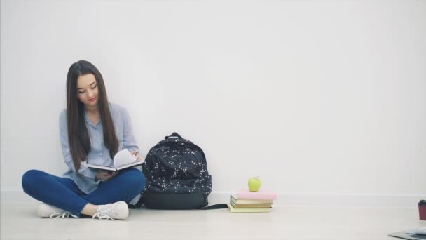 Натхненний азіатський студент, сидячи в позі лотоса, перевертаючи сторінки свого записника, вказуючи пальцем вгору, махаючи привіт в сторону, посміхаючись . — стокове відео