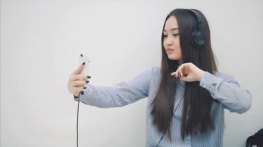Komik, genç Asyalı bir kız, kulaklıkla durup, müzik dinliyor, selfie çekiyor, poz veriyor, surat asıyor, sonra biriyle mesajlaşıyor..