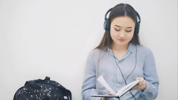 Натхненна молода азіатська дівчина сидить на підлозі, робить домашнє завдання, пише, слухає музику, танцює . — стокове відео