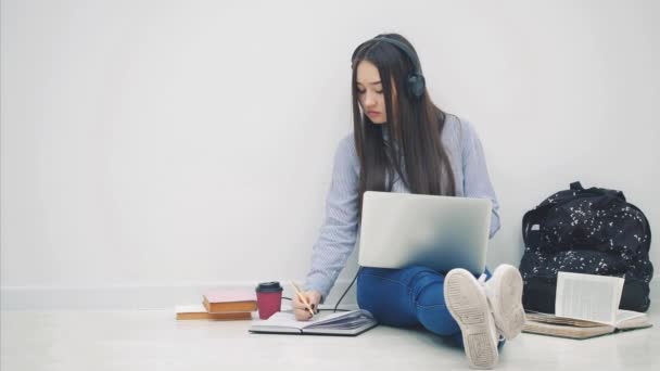 Söt asiatisk flicka sitter på golvet, deltar i processen att förbereda sig för examen, sedan höja upp ett papper med ord Tentamen skrivet på den. Omgiven av läromedel. — Stockvideo