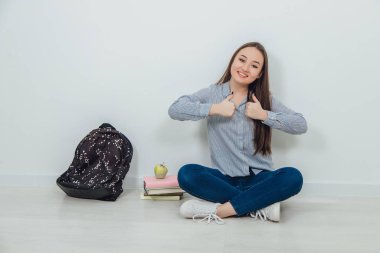 Güzel gülümseyen Asyalı öğrenci loto pozisyonunda oturmuş, parmağını kaldırıyor..