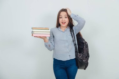 Sırt çantası elinde kitap destesiyle duran Asyalı zeki kız öğrenci, şaşırmış yüz ifadesi..