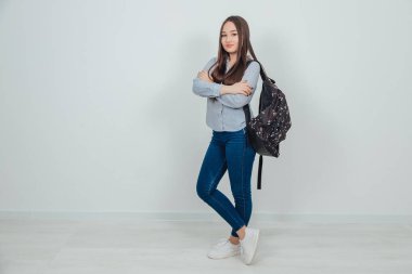 Sırt çantalı, elleri bağlı, bacak bacak üstüne atmış, kendinden emin, havalı Asyalı genç kız..