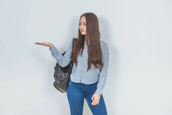 Натхненна молода азіатська дівчина, що стоїть з рюкзаком, ковзає по плечу, піднімаючи її відкриту долоню з копійкою для тексту або продукту . — стокове фото