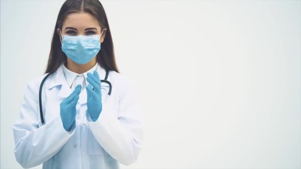 Güzel bayan doktor, tıp üniforması içinde kameraya bakıyor, ellerini ovuşturuyor, sanki vahşi bir şey yapmayı düşünüyormuş gibi.. — Stok video