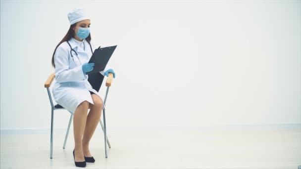 Terapista stanco seduto sulla sedia, togliersi la maschera medica, gettare gli appunti a terra, massaggiare il suo tempio, sospirare pesantemente . — Video Stock