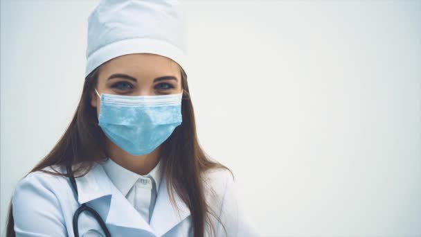 젊은 여성 의사가 의자에 앉아 의료용 마스크를 벗고 환한 미소를 짓고 있다. — 비디오