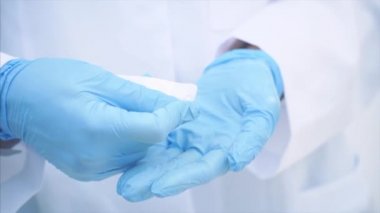 Doktor elleri, tek kullanımlık tıbbi eldivenler giymiş, su toplamadan iki beyaz hap alıyor..