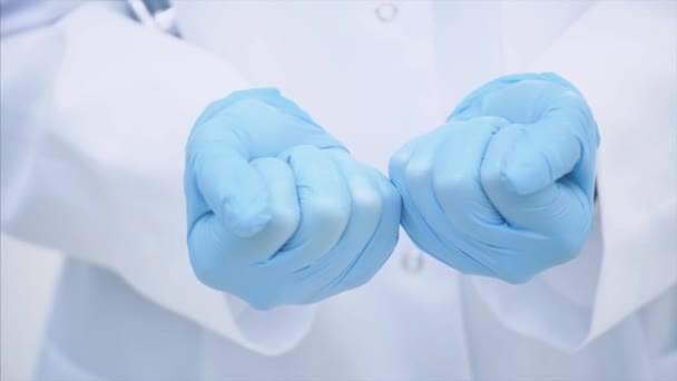 Muchas pequeñas pastillas blancas en las manos de los médicos vestidos con los guantes médicos desechables . — Vídeos de Stock