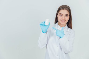 Güzel, genç bir stajyer kız elinde bir şişe hap tutuyor, parmağını ona doğrultuyor, gülümsüyor..