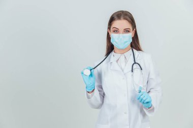 Steril eldiven takmış, steteskoplu ve kameraya bakan genç bir doktorun portresi..