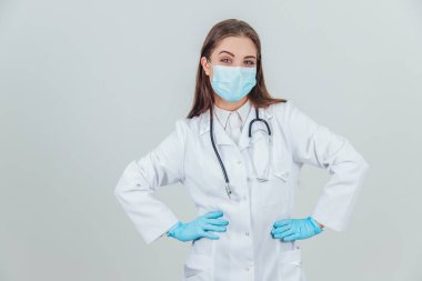 Steril eldiven ve steteskopla genç bir doktorun portresi. Kameraya bakıyor, ellerini havada tutuyor..
