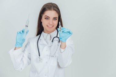 Gülümseyen genç bayan doktor şırıngalarla ellerini kaldırıyor..
