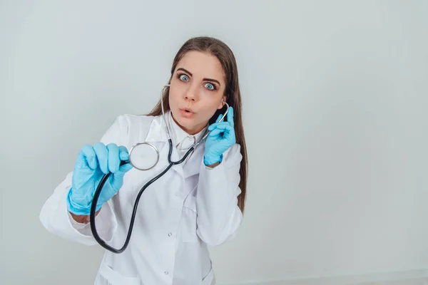 Aantrekkelijke jonge dokter met stethoscoop, doodsbang voor wat ze heeft gehoord. Uitdrukkend gezicht. — Stockfoto