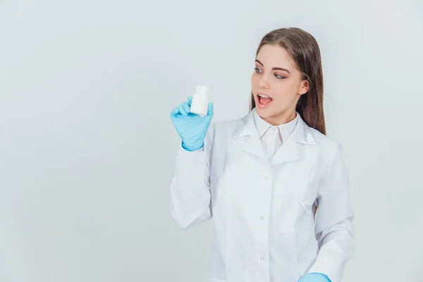 Docela inspirovaná mladá internistka držící v ruce lahvičku prášků. Výrazná tvář. — Stock fotografie