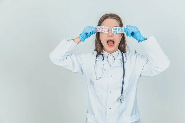Vtipná mladá internistka si pohrávala, skrývala oči za puchýřky barevných pilulek, otvírala ústa. — Stock fotografie