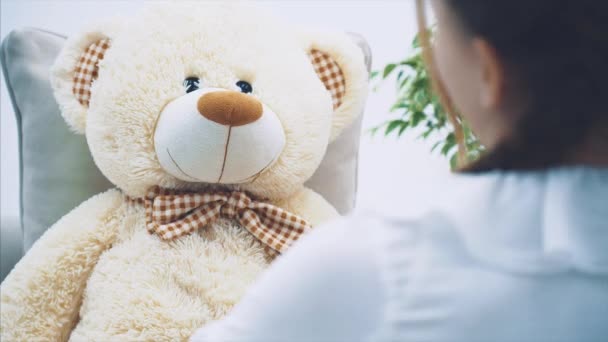 Cute little girl sitting, talking with her teddy, berating it, shaking her finger, waving her hands. — Stock Video