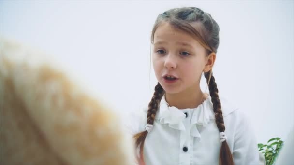 Schattig klein meisje zittend, pratend met haar teddy, zwaaiend met haar handen, vouwend, beledigend kijkend. — Stockvideo