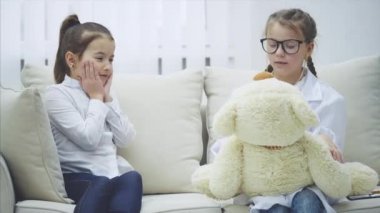 Oyuncak ayıyla oynayan iki tatlı çocuk. Bir kız boynunda steteskop olan bir doktor, diğeri de oyuncak ayı sahibi. Doktor ayılara teşhis koyuyor..