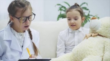 Oyuncak ayıyla oynayan iki tatlı çocuk. Bir kız boynunda steteskop olan bir doktor, diğeri de oyuncak ayı sahibi. Doktor ayılara teşhis koyuyor..