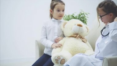 Oyuncak ayıyla oynayan iki tatlı çocuk. Bir kız boynunda steteskop olan bir doktor, diğeri de oyuncak ayı sahibi. Doktor ayılara teşhis koyup konuşuyor..