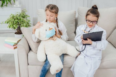 Beyaz ayıcık hasta. Oldukça küçük bir doktor pofuduk hastasına ilaç yazıyor..