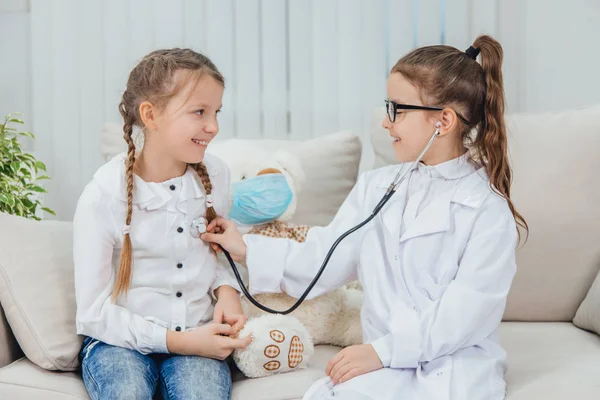 Inquisitive girls playing the game: doctor and patient. Little doctor listening through stethoscope the heartbeat of her patient.