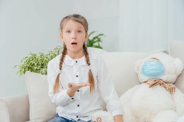 Lekarz przepisał tabletki na pluszowego misia, ale mała dziewczynka nie rozumie motyki na medycynę. Siedzi z zakłopotaną twarzą.. — Zdjęcie stockowe