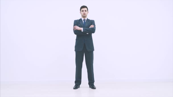 Poważny przystojny biznesmen stojący, składający ręce, spoglądający pewnie w kamerę. — Wideo stockowe