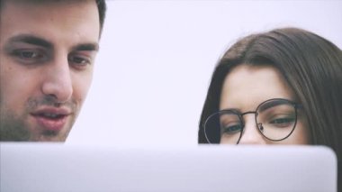 Genç iş çifti ayakta duruyor, dizüstü bilgisayarda bir şeye bakıyor, önemli soruları tartışıyor, düşünüyor..