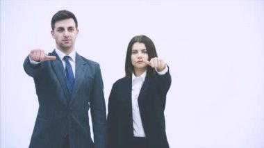 İş adamı ve kadın yan yana dururlar, ne yapacakları konusunda tereddüt ederler, başparmaklarını yukarı ya da aşağı kaldırırlar. Sonunda onay veriyorlar, gülümsüyorlar, onaylıyorlar..