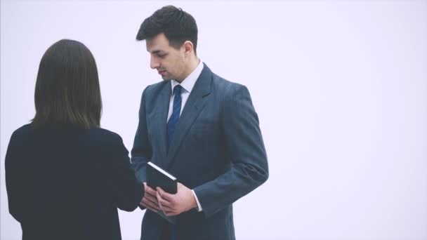 Partnerzy biznesowi omawiają pewne kwestie związane z pracą. Kobieta stojąca tyłem do kamery, pokazująca zdjęcia mężczyzny na notatniku. — Wideo stockowe