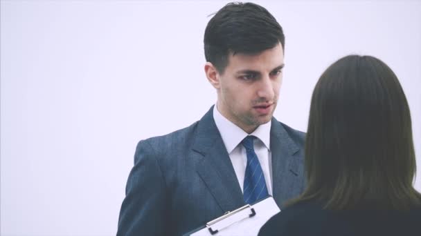 Successful businesspartners standing, discussing some work issues. Blurred woman standing back to the camera, holding clipboard. — 비디오