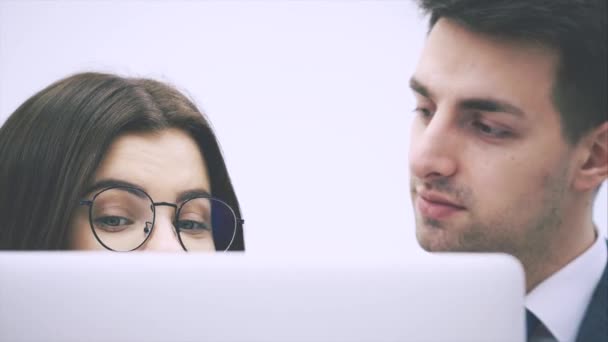 Young business couple standing, looking at something in the laptop, discussing important questions, thinking. — Stock Video