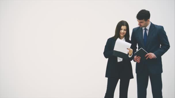 Pretty businesswoman standing with clipboard in her hands, reading checklist. Businessman on her side is listening to her, nodding. — Stock video