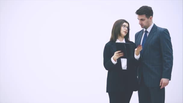 Bella donna d'affari in piedi con tablet in mano, spiegando qualcosa al suo partner. L'uomo d'affari dalla sua parte sta ascoltando, annuendo . — Video Stock