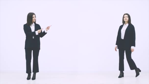 Two businesswomen appearing on the white background, using different gestures, giving thumb up, pointing fingers, folding hands. — ストック動画