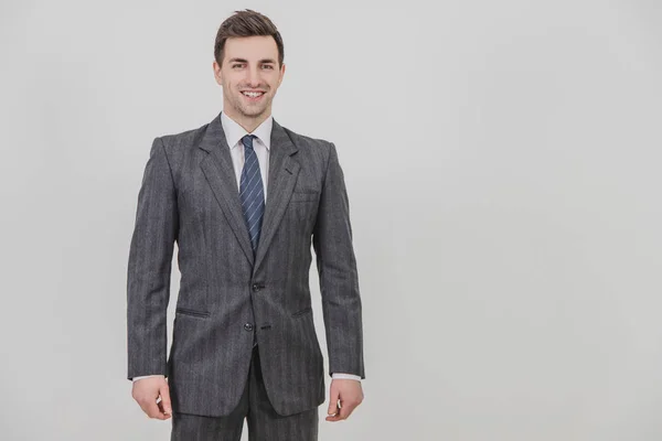 Bello uomo d'affari vestito grigio e cravatta, in piedi, sorridente . — Foto Stock