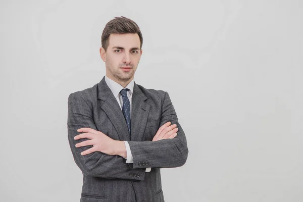 Serious handsome businessman standing with his hands folded, looking confidently at the camera. — Stock Photo, Image