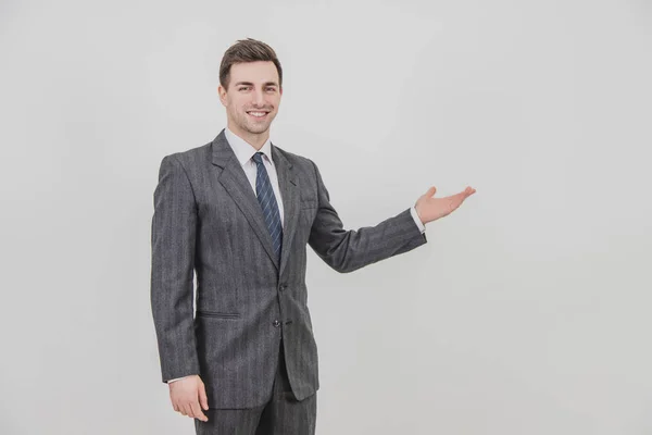 Exitoso hombre de negocios guapo de pie, presentando un proyecto, apuntando sus manos al espacio de copia para texto o producto . — Foto de Stock