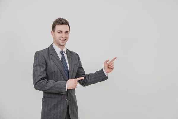 Successful handsome businessman standing, presenting a project, pointing his fingers at the copyspace for text or product. — Stock Photo, Image