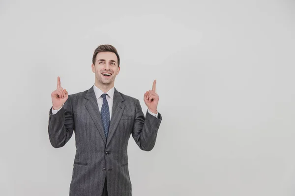 Successful handsome businessman standing, presenting a project, pointing his fingers up, smiling. — Stock Photo, Image