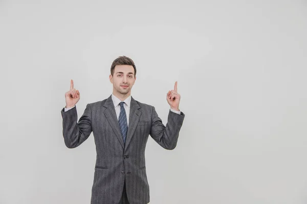 Successful handsome businessman standing, presenting a project, pointing his fingers up, smiling. — Stock Photo, Image