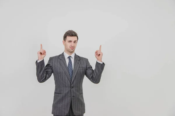 Exitoso hombre de negocios guapo de pie, presentando un proyecto, señalando con los dedos hacia arriba, frunciendo el ceño . — Foto de Stock