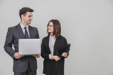 Genç iş çifti ayakta, dijital tablet ve dizüstü bilgisayarlarıyla birbirlerine bakıyorlar..